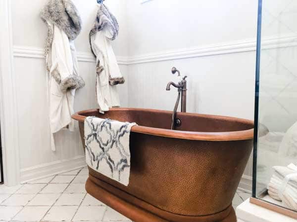 A copper free standing bathtub in a gorgeous bathroom.
