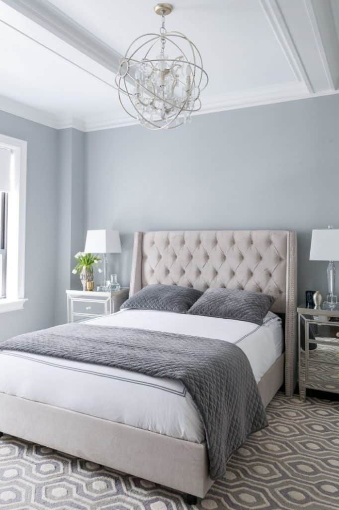 A bedroom with Coventry Gray on the walls, a cream tufted headboard and mirrored nightstands.