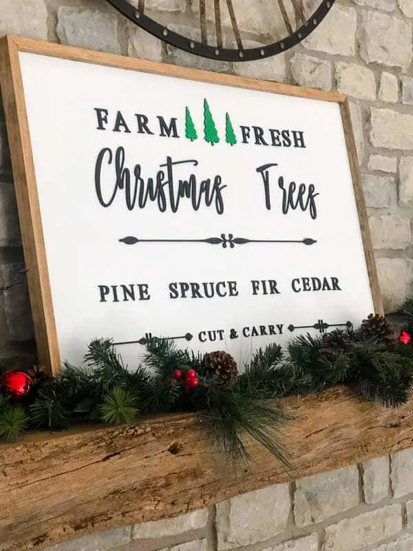A Christmas wood sign on my mantle with pine garland.