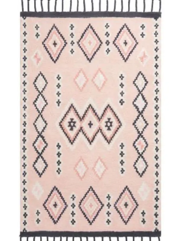 A rug with tassles, a pink background and a black diamond pattern on it.