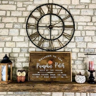 My stone fireplace with reclaimed wood mantel and oversized black and gold clock hanging on the stone.
