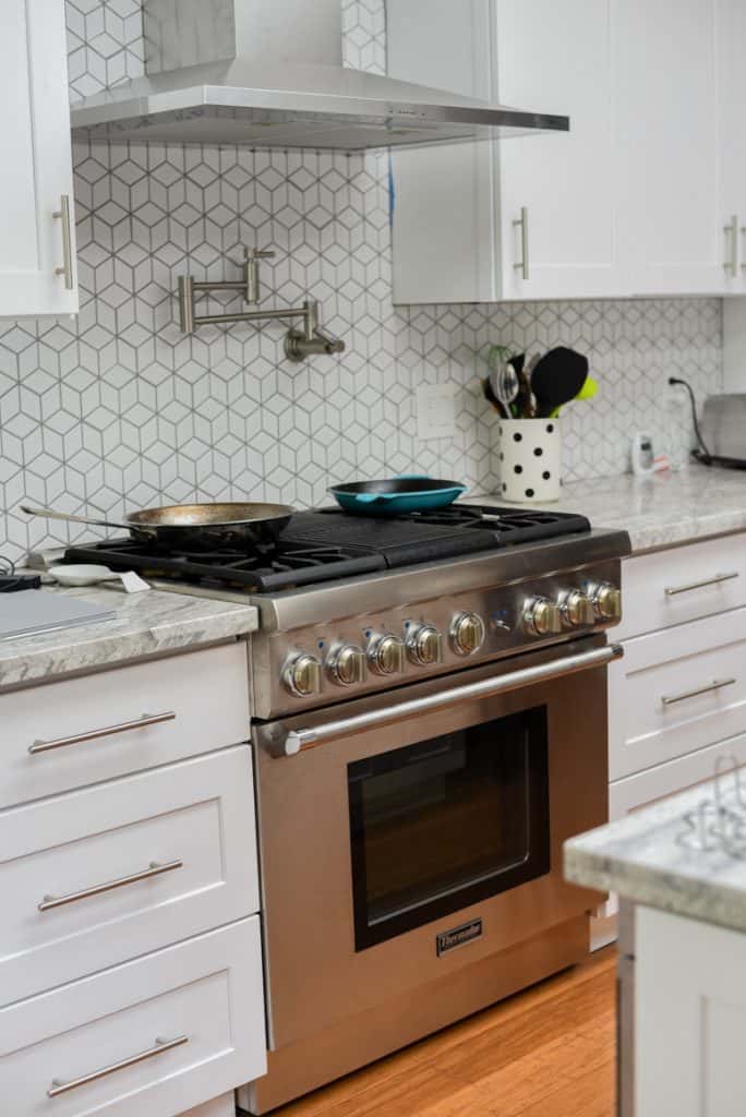 A farmhouse style kitchen with silver pulls on both the cabinets and drawers.