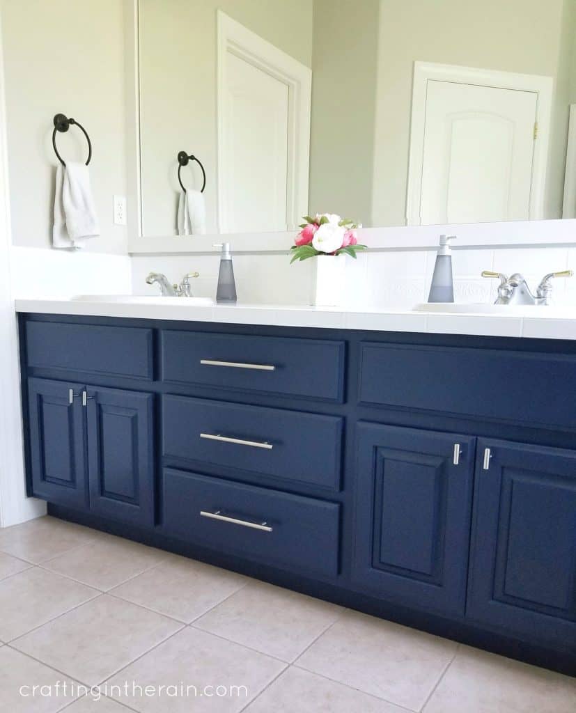 A navy blue vanity in a bathroom with silver handles and pulls that match.