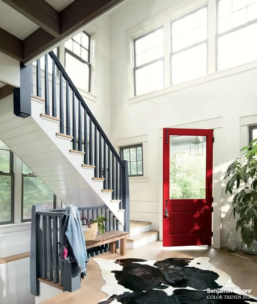 A view from the inside of the home with a red door that has a large window in it.