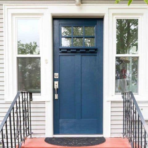 A white house with a craftsman dark blue door.