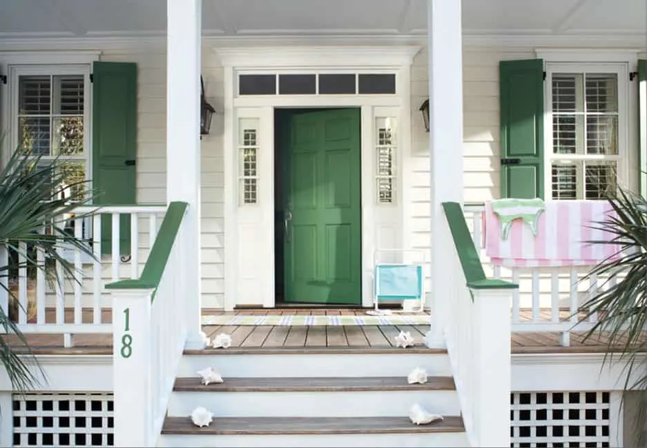 A front door that is green with light yellow siding.