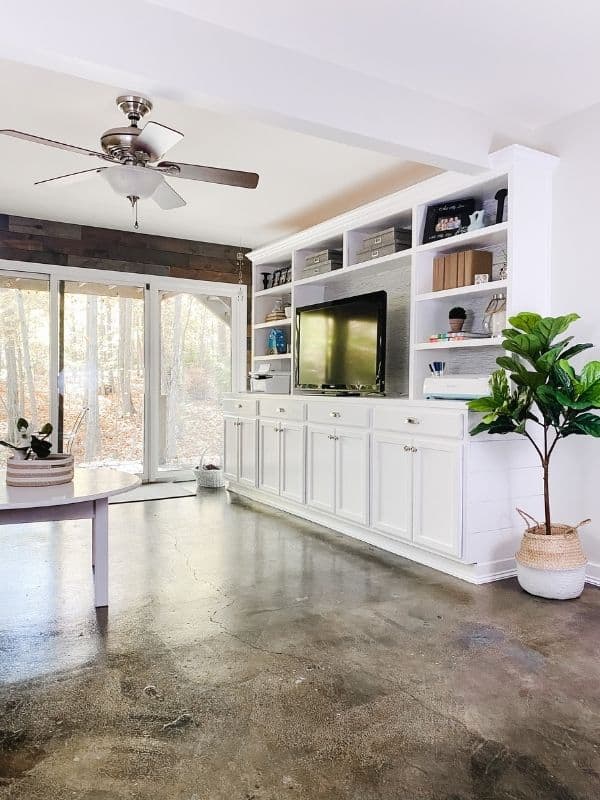 A view of my stained concrete floors with my white DIY built-ins and a fiddle leaf fig tree in a basket.