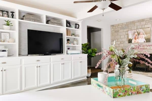 An office/den with white builtins, gray/cream walls and a stone fireplace.