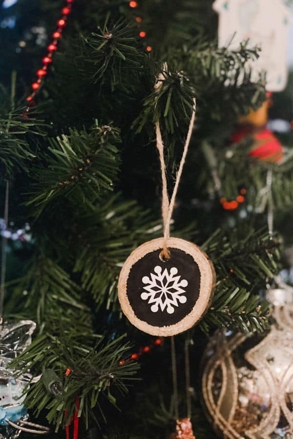 Wood slice ornament with a snowflake on it hanging on the Christmas tree.