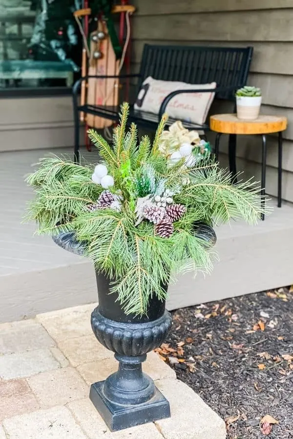 Front porch Christmas pots decorated with pine branches, pine cones and white balls.