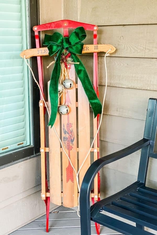 An antique sled with sleigh bells and a green bow.