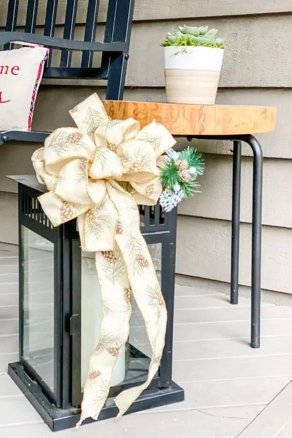 A lantern with a big bow and a sprig of greenery.