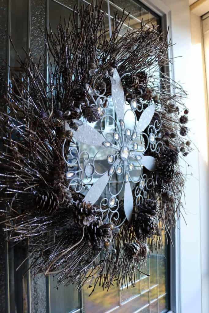 A natural pinecone wreath with sparkles on it and a large snowflake in the middle.