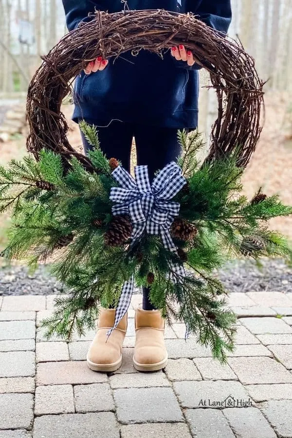 My daughter holding the winter wreath with a buffalo check bow.