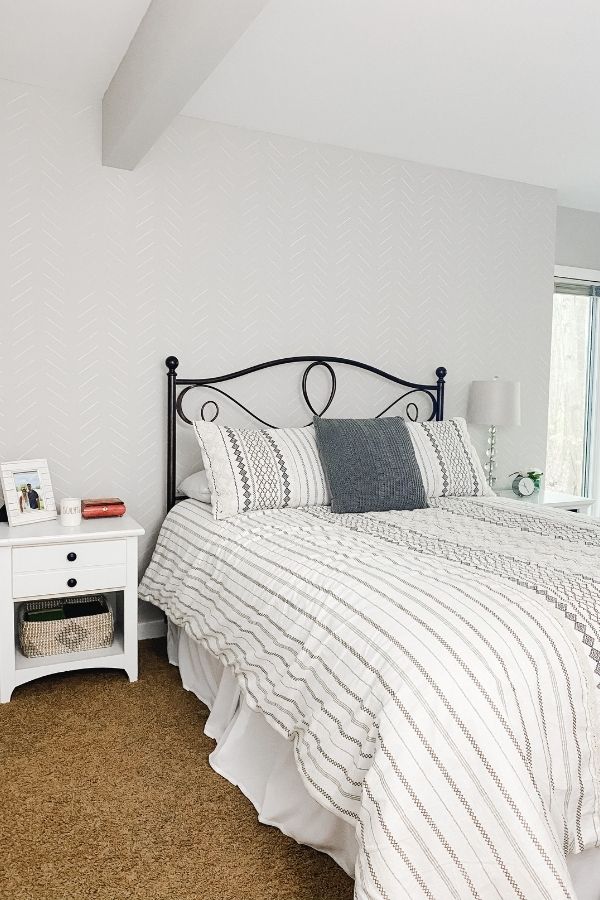 Agreeable Gray on the walls with an iron headboard and a white and gray comforter.