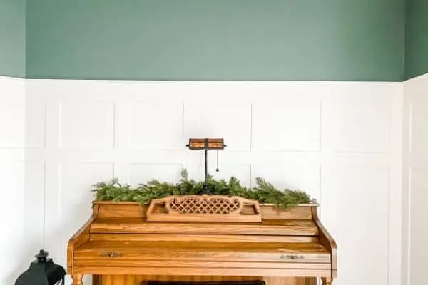 DIY Board and batten with blue green paint above and my piano with greenery on top.