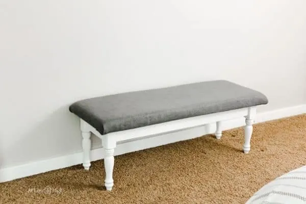The finished bench with the painted base and a gray fabric top.