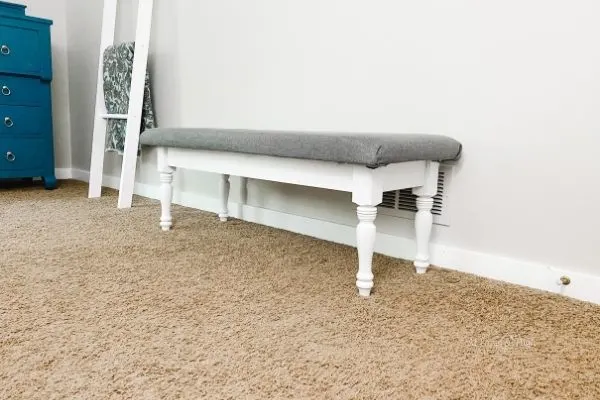 The finished bench with a white painted base and a gray fabric top.