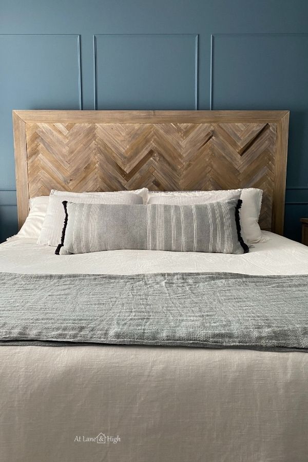 A herringbone headboard with white bedding and a light blue throw blanket at the foot of the bed.