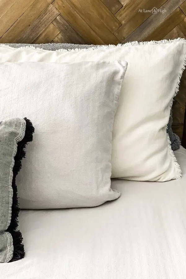 The new bedding of white comforter and shams with gray flannel sheets against the herringbone headboard.