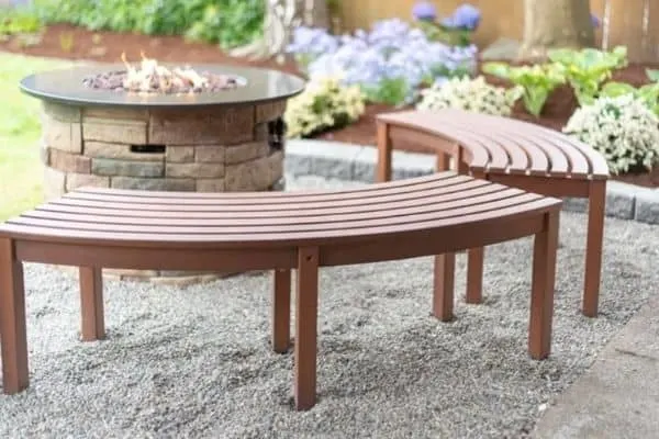This pea gravel patio area has curved benches and a fire pit.
