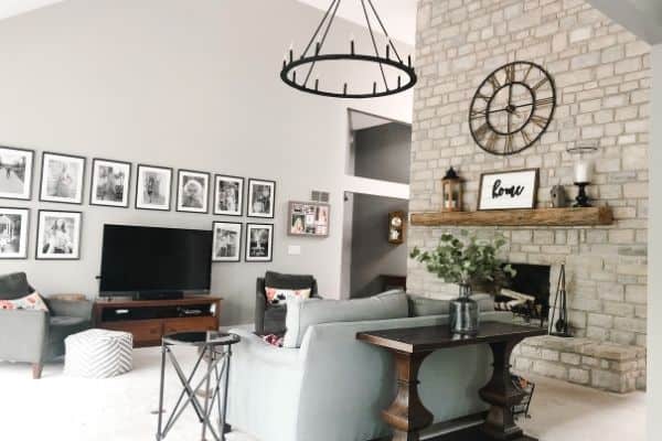 My family room with a wagon wheel chandelier hanging from my vaulted ceiling and a stone fireplace and reclaimed wood beam mantel.