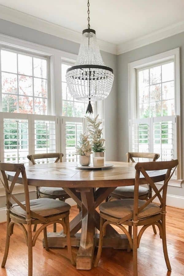 Passive in the dining room with tons of windows, wood table and chairs and a crystal beaded chandelier.