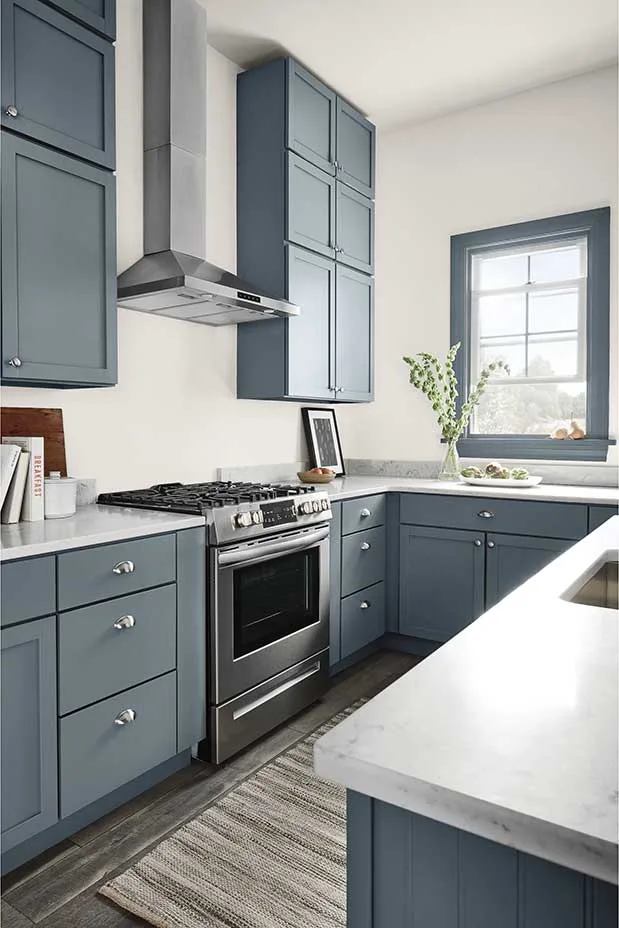 A kitchen with alpaca on the walls and a blue gray on the cabinets and trim.