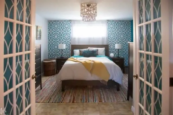 A bedroom with a stenciled headboard wall and diy light fixture.