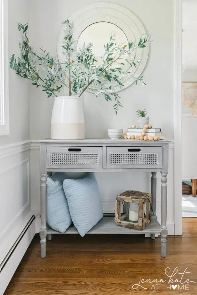 An example of Stonington Gray in an entry with a gray wash console table and a large vase with olive branches in it.