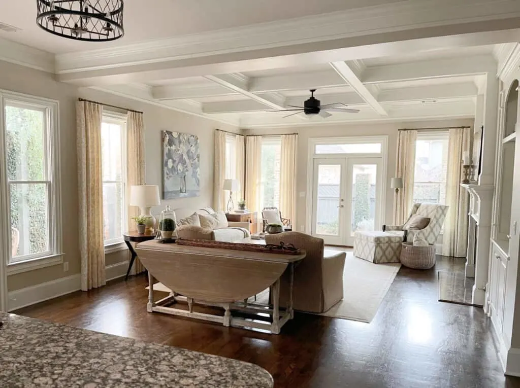 A family room with coffered ceilings, tons of windows and accessible beige on the walls.