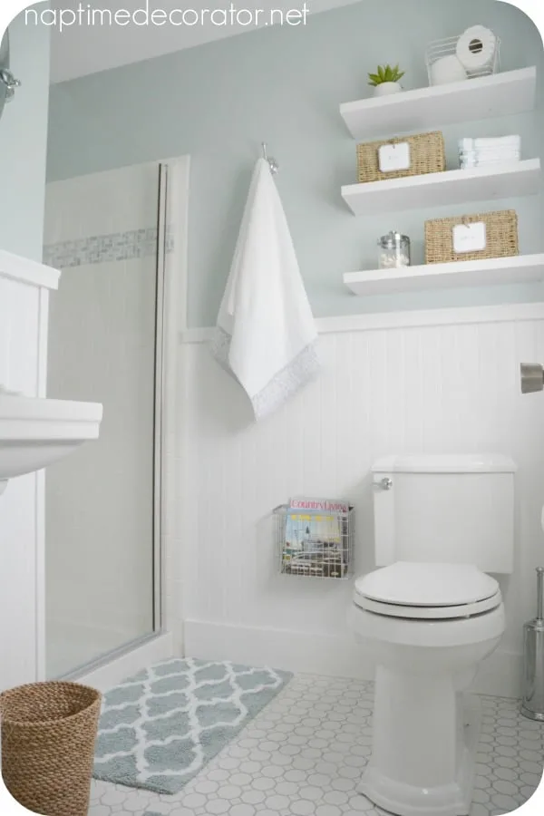 This bathroom has white wood wainscoting and a blue green paint color.