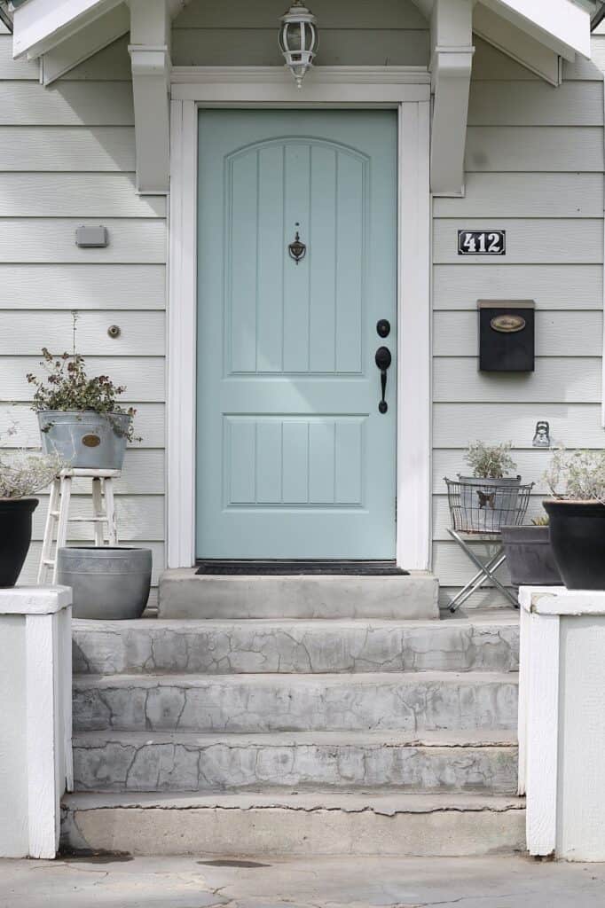 This exterior of the home has gray siding and a beautiful blue-green door.