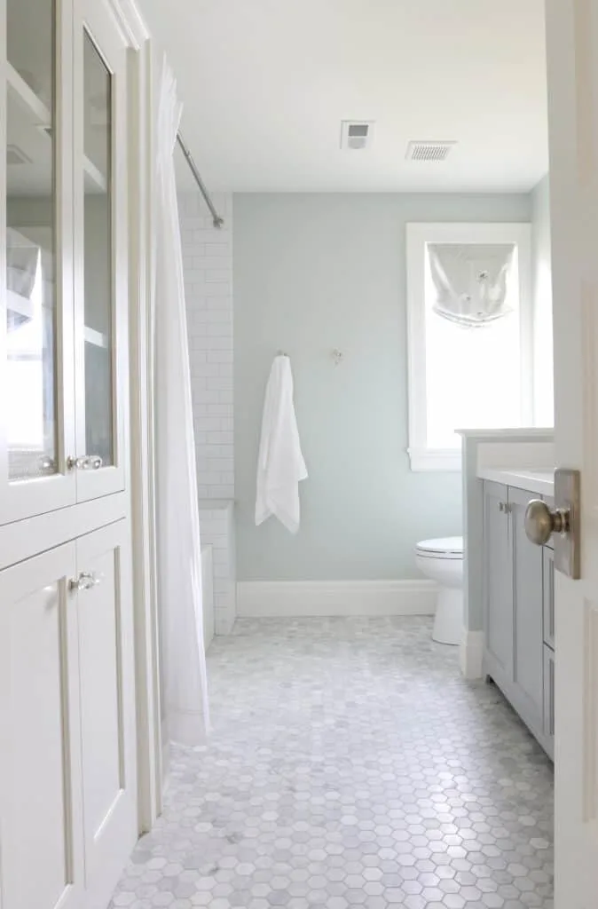 A bathroom with lots of marble, white cabinetry and Sea Salt on the walls.