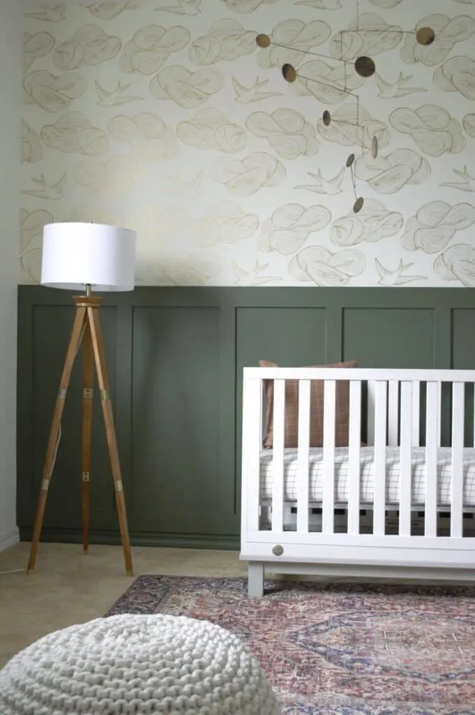 Backwoods used on wainscoting in a nursery with a white crib and wallpaper above.