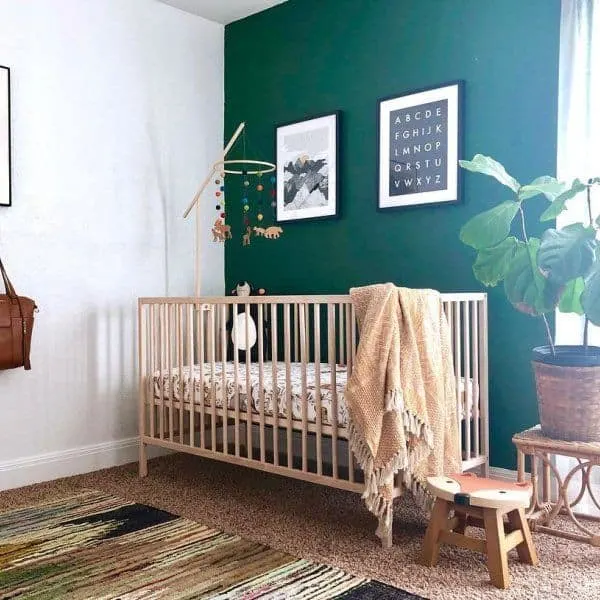 A nursery with an accent wall behind a light wooden crib in Evergreens.
