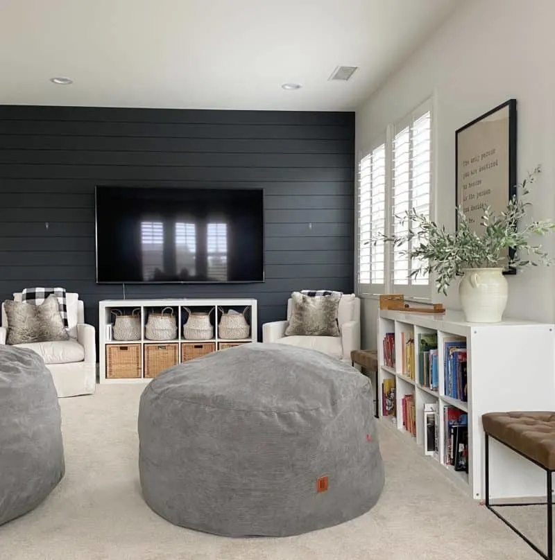 A family room with French Beret painted shiplap on the TV wall and the other walls are white.