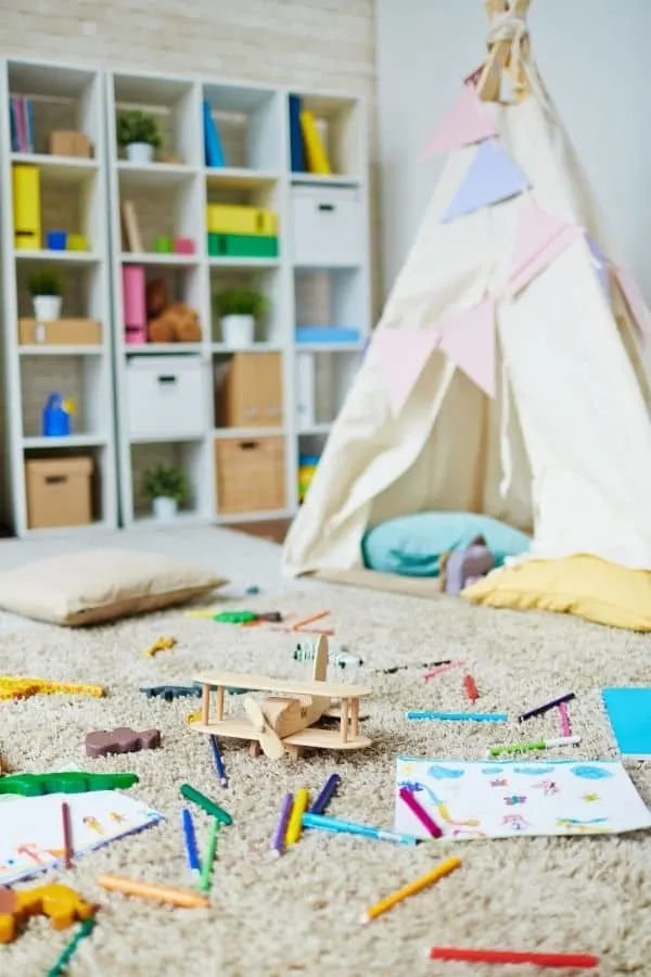 Here is a teepee in a kids play room and lots of toys laying around the floor.