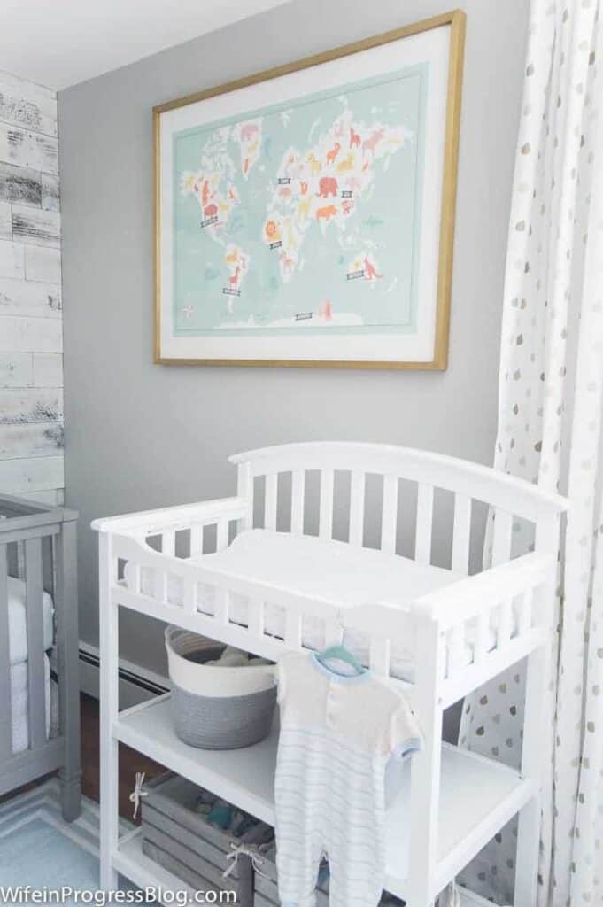 Gray painted walls in a nursery with a white changing table and a world map hanging above.