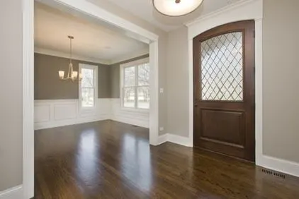 An entry way with wood floors, white trim and a beautiful wood door.