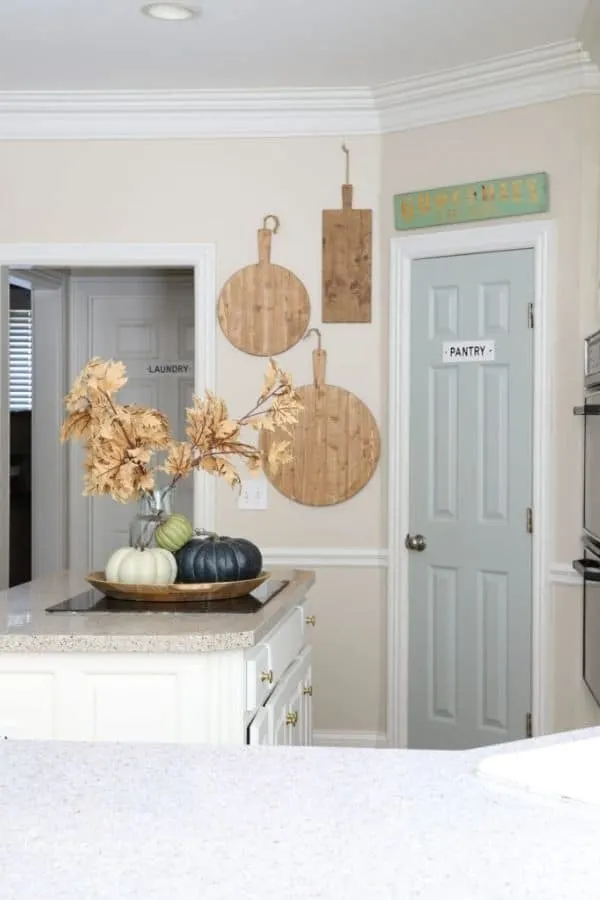 A kitchen with beige walls and the pantry door painted in Comfort Gray.