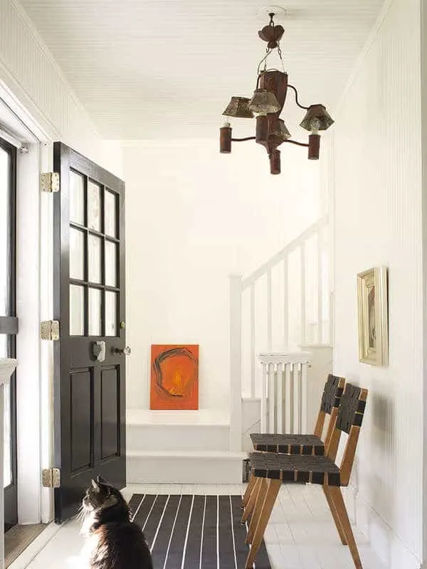 This entryway has. white dove on the walls and lots of black accents in the door and chairs.