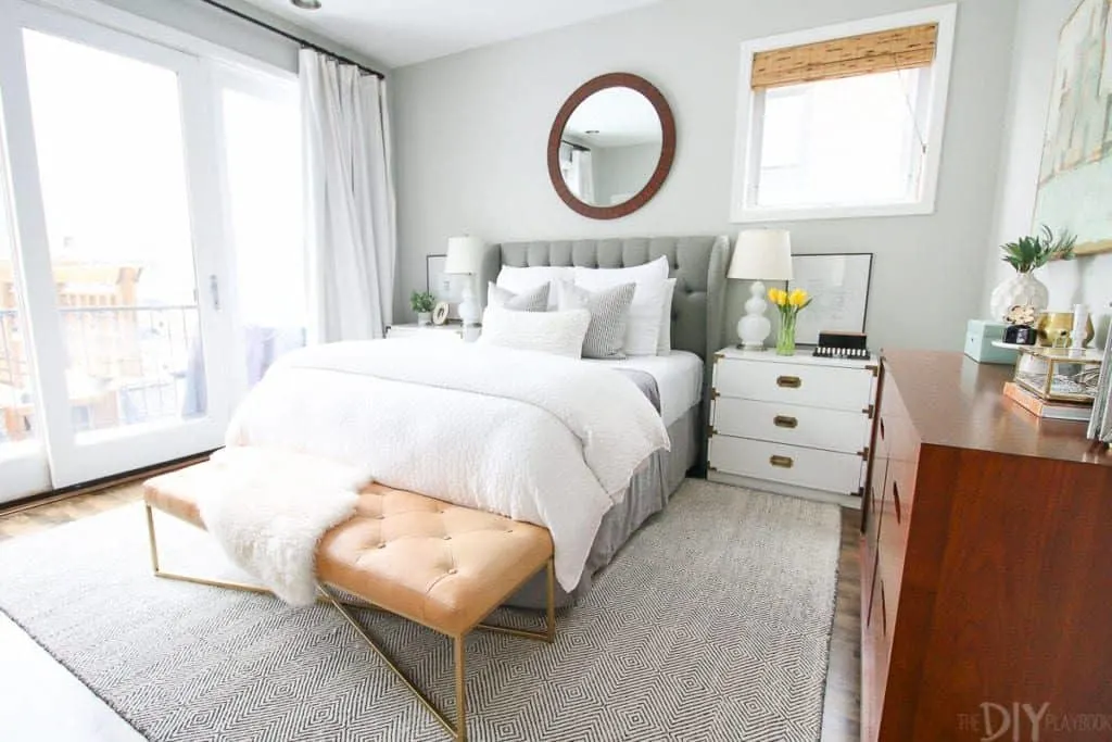 Benjamin Moore Gray Owl on the walls of a bedroom that has huge sliding glass doors, a gray upholstered bed with white linens.