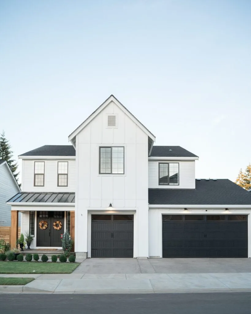 A farmhouse style home with the exterior painted in Pure white with black front door and garage doors.