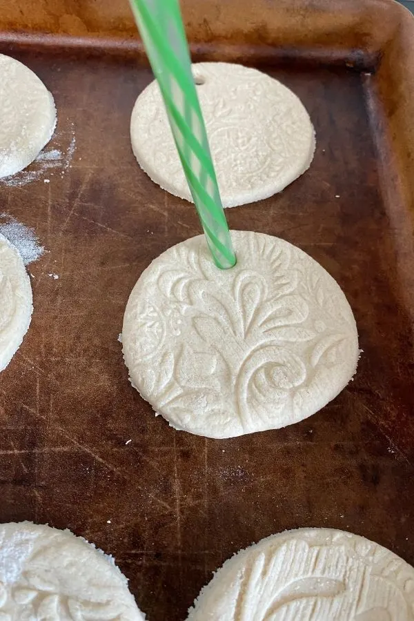 Using a straw to puncture a hole in the ornament for hanging.