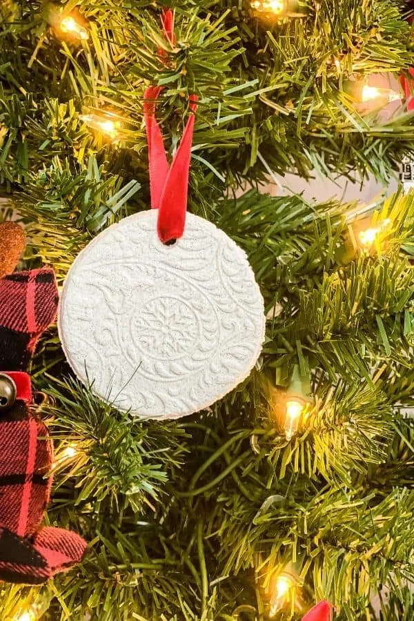 Salt dough ornament hanging on a Christmas tree with a red ribbon.