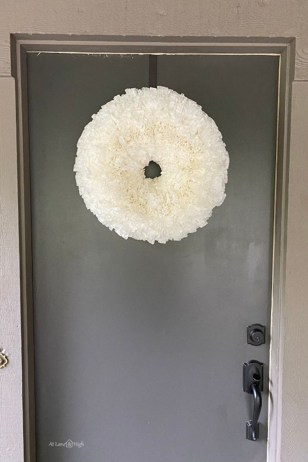 The coffee filter wreath is hanging on my front door which is painted a dark color, almost black, and the house is a medium brown color.