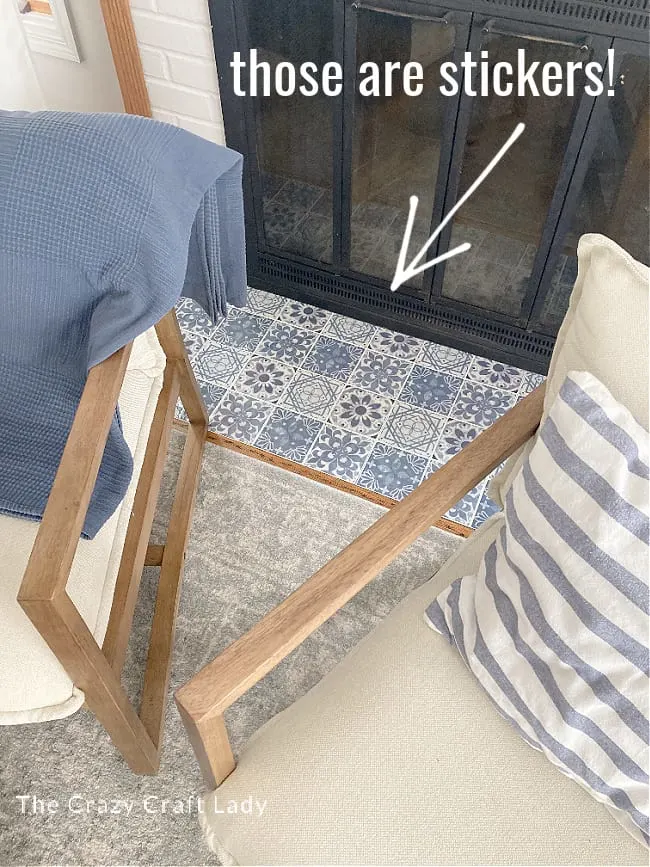 Tile stickers on a fireplace hearth in blue and white with two chairs flanking the fireplace.