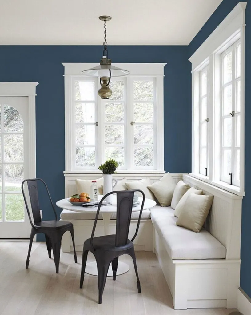 Sherwin Williams Salty Dog on the walls of a breakfast nook.  There is white trim on the windows and a white banquette.