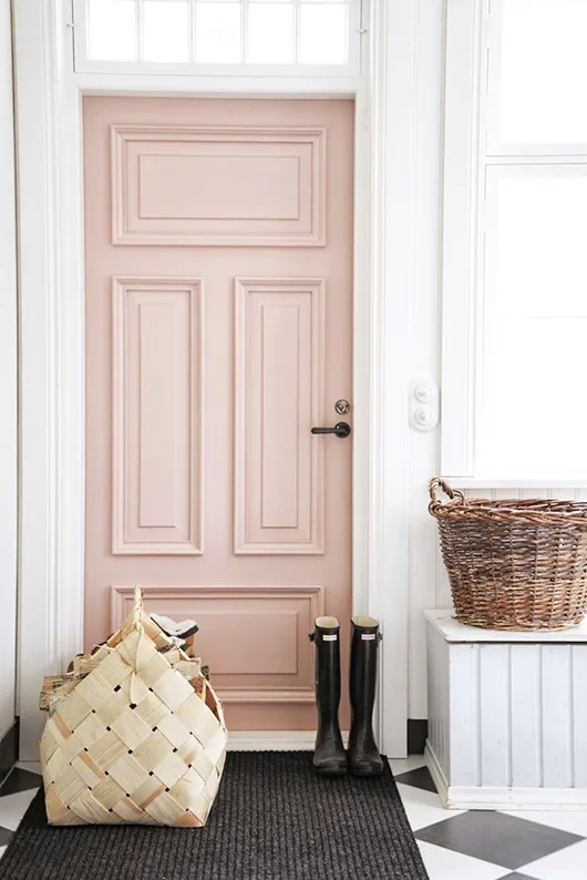 A blush paint color on a door with a basket and black rain boots in front of it.